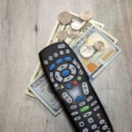 A TV remote framed by dollar bills and loose change