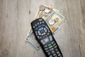 A TV remote framed by dollar bills and loose change