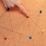 Finger connecting dots on a cork board network concept