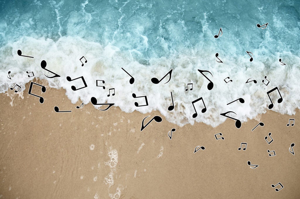 Sounds of nature. Musical notes scattered above rolling ocean waves on sandy beach