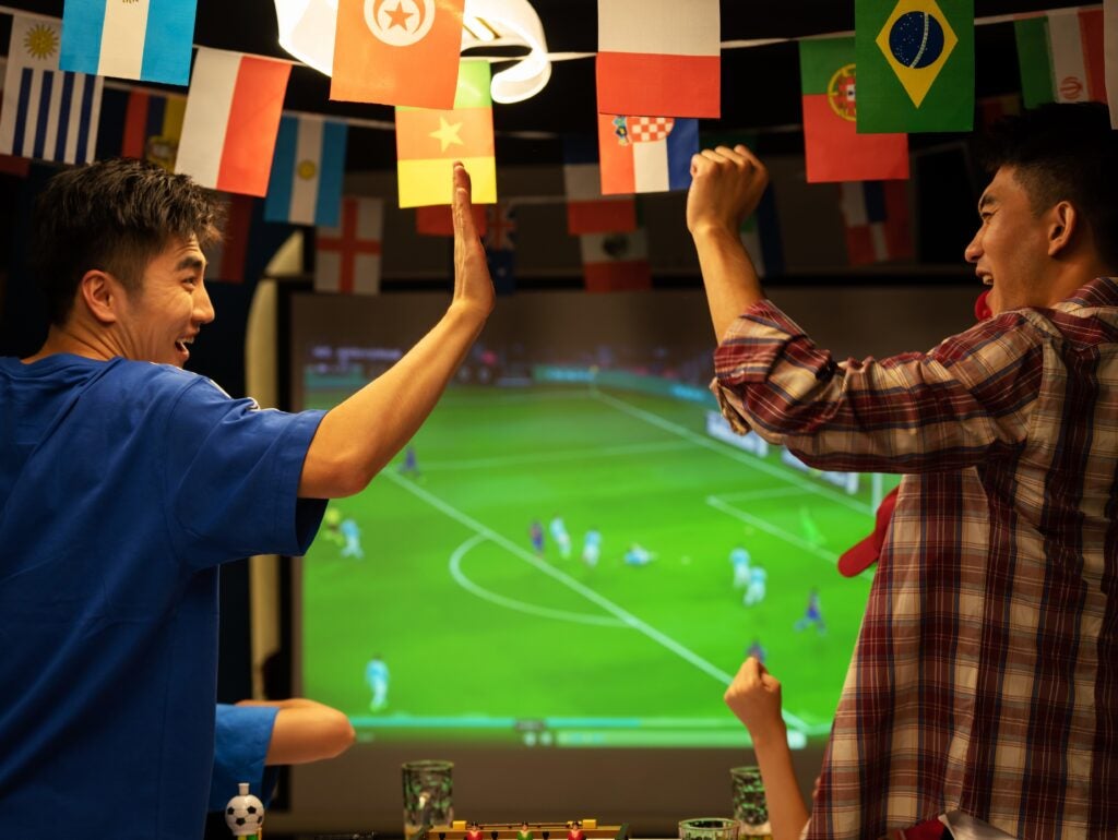 Friends high-five while watching a football soccer match